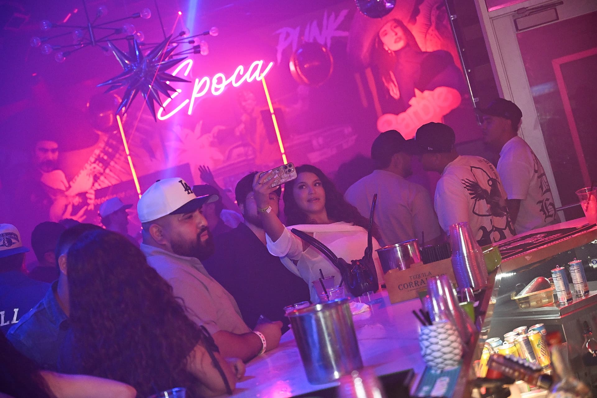 Guests at the bar under the Época neon sign