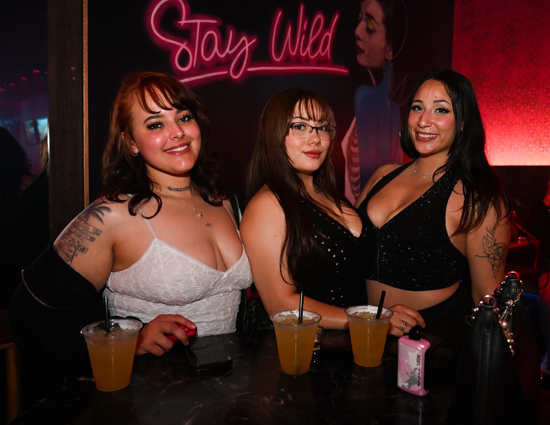 Guests under the Stay Wild neon at Época Cantina